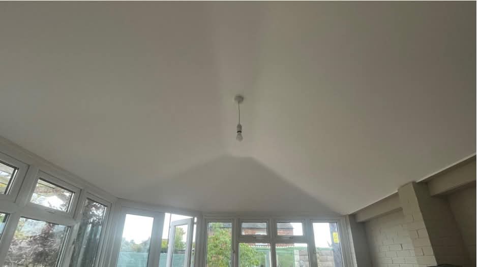 Warm, bright conservatory interior with a Shire solid roof, plastered ceiling, downlights and skylights